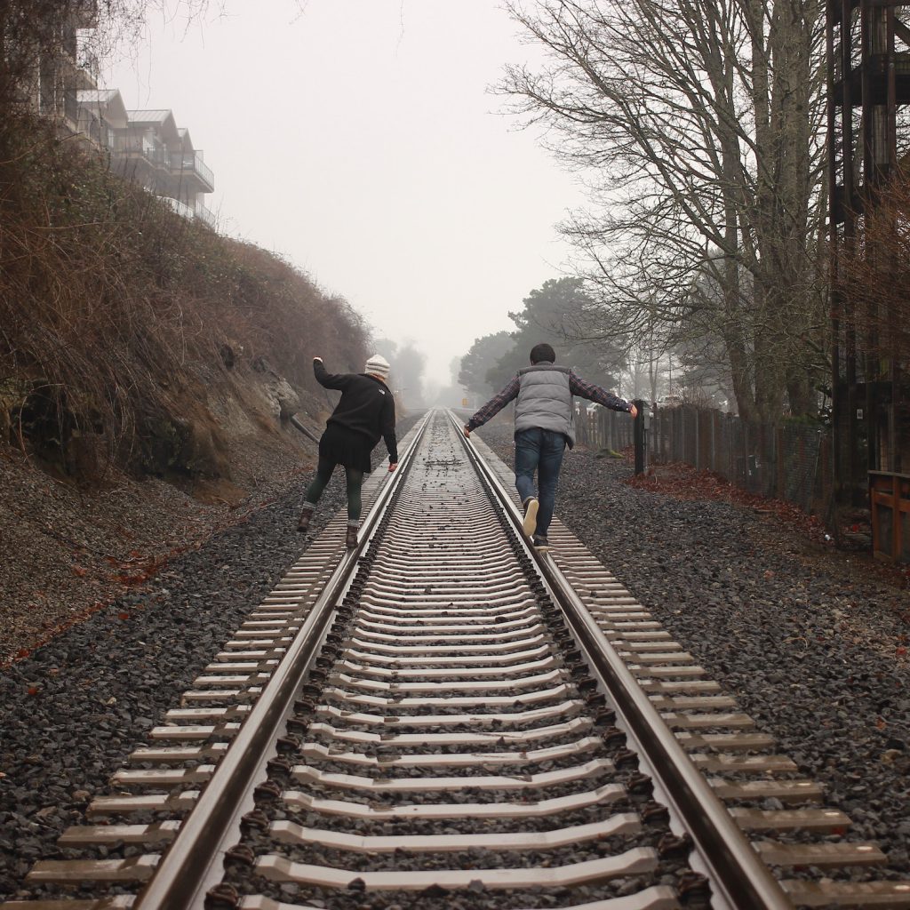 decorative image: two people walking on train tracks