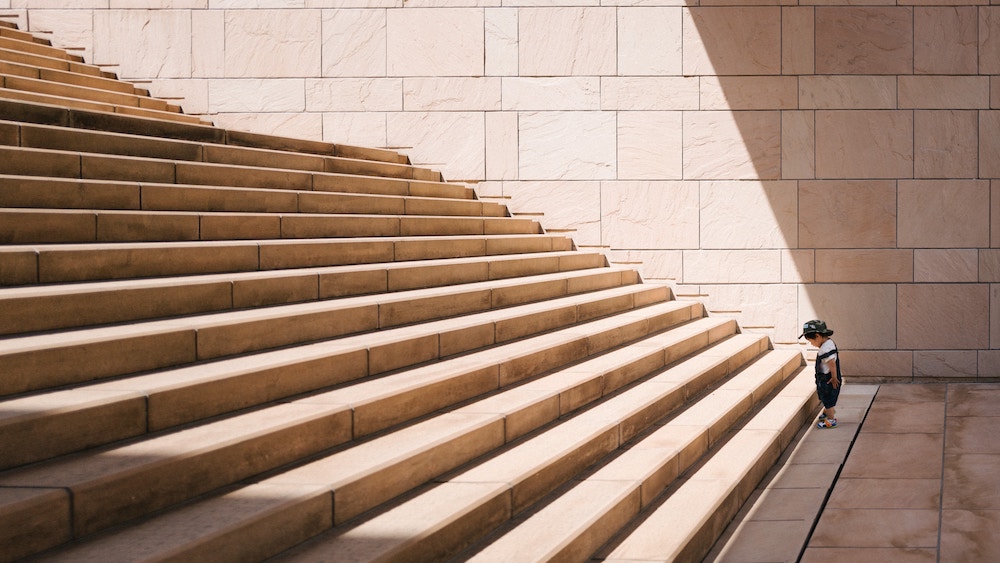 child staring up a tall flight of stairs